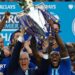 Leicester City manager Claudio Ranieri and captain Wes Morgan lift the Premier League trophy while surrounded by euphoric Foxes players