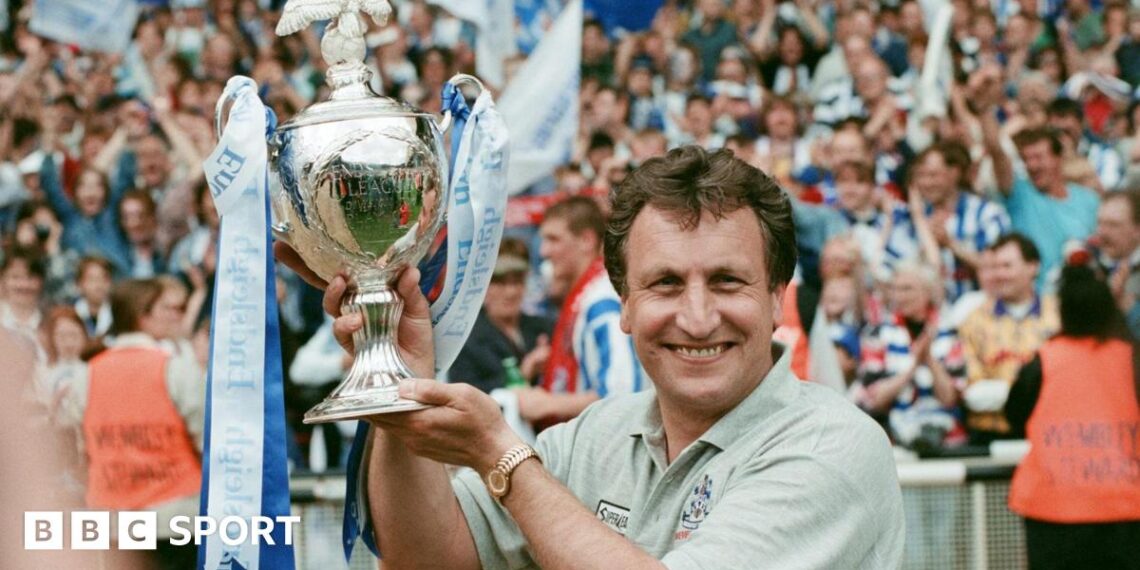 Neil Warnock holds up the play-off trophy at Wembley adorned with blue and white ribbons