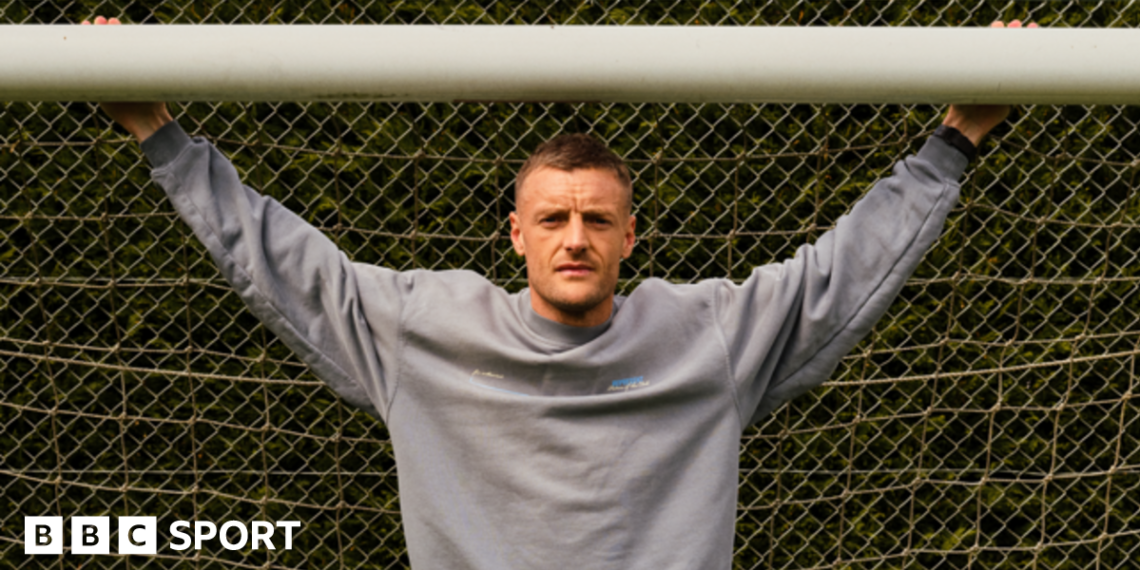 Jamie Vardy stood in a goal with his arms outstretched and holding onto the crossbar