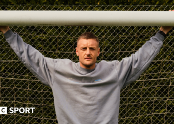 Jamie Vardy stood in a goal with his arms outstretched and holding onto the crossbar