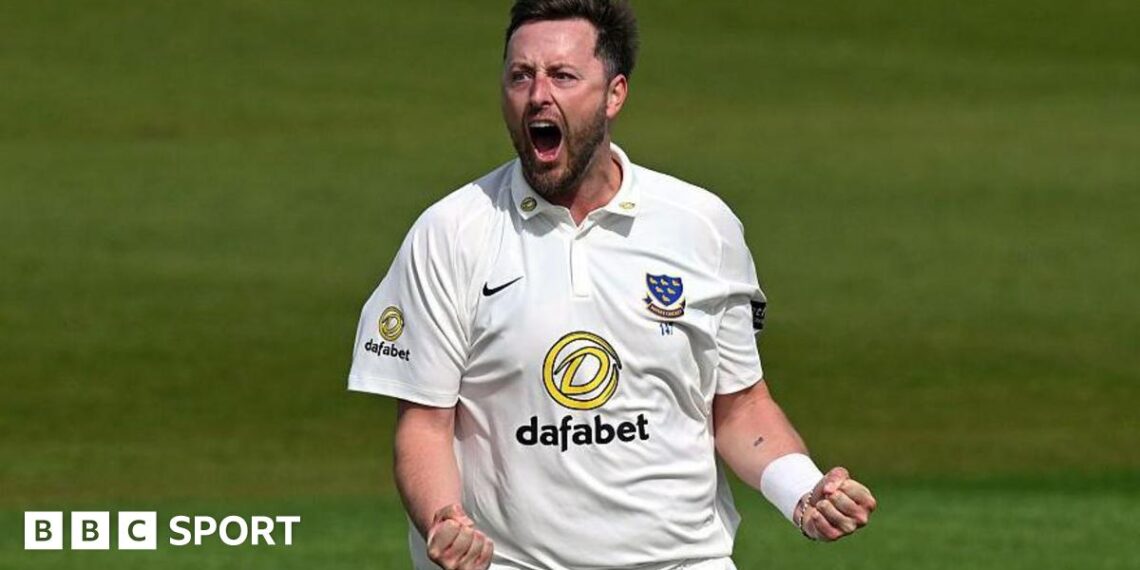 Ollie Robinson, wearing a white Sussex shirt, roars and clenches both of his fists in front of him to celebrate a wicket