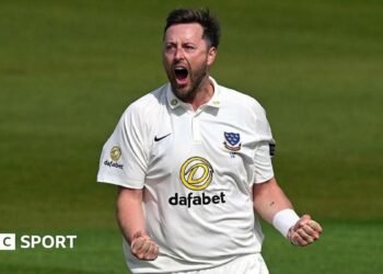 Ollie Robinson, wearing a white Sussex shirt, roars and clenches both of his fists in front of him to celebrate a wicket