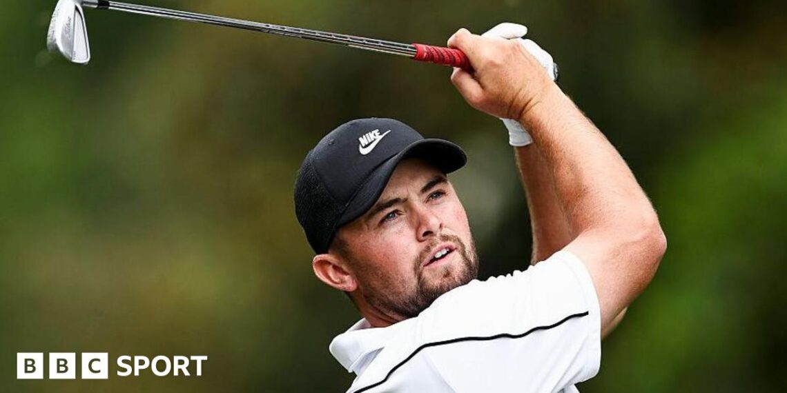 Alex Fitzpatrick watches his ball after playing an iron shot, with the club above his head