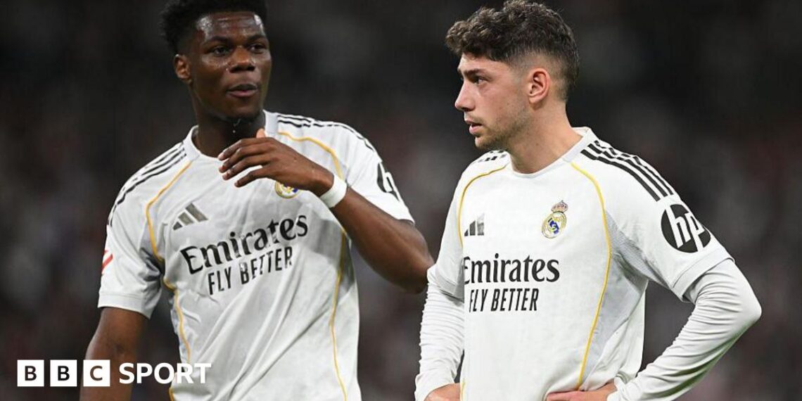 Real Madrid's Aurelien Tchouameni and Federico Valverde stand next to each other in a match, wearing the club's white kit