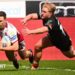 Wigan Warriors full-back Jai Field, in white and red, dives over the line to score a try as a Bradford player tries to tackle him