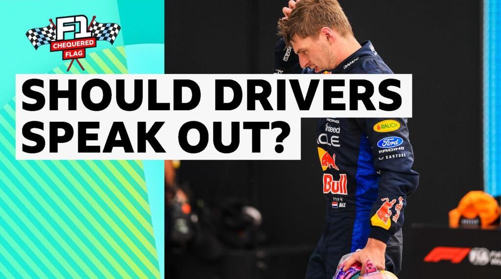Max Verstappen dressed in Red Bull race suit with a hand to his head