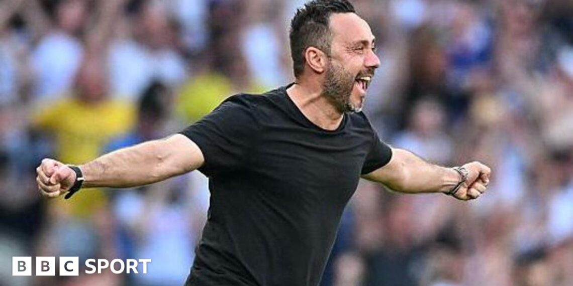 Roberto de Zerbi celebrates with a broad smile and arms outstretched as he runs on to the pitch in a black T-shirt
