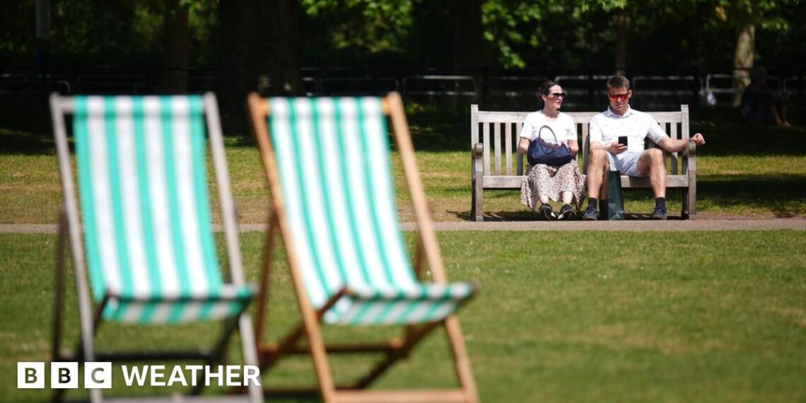 A man and a woman sitting on a bench in a London park on the hottest day of the year so far