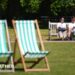 A man and a woman sitting on a bench in a London park on the hottest day of the year so far