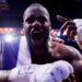 Daniel Dubois leans over the ropes of a boxing ring and holds up his hand