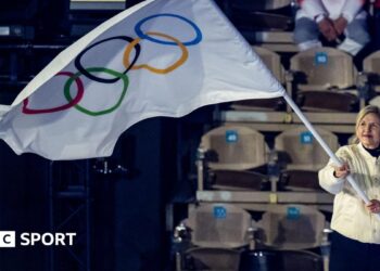 IOC president Kirsty Coventry waving an Olympic flag