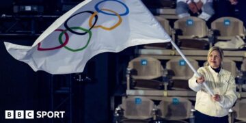 IOC president Kirsty Coventry waving an Olympic flag