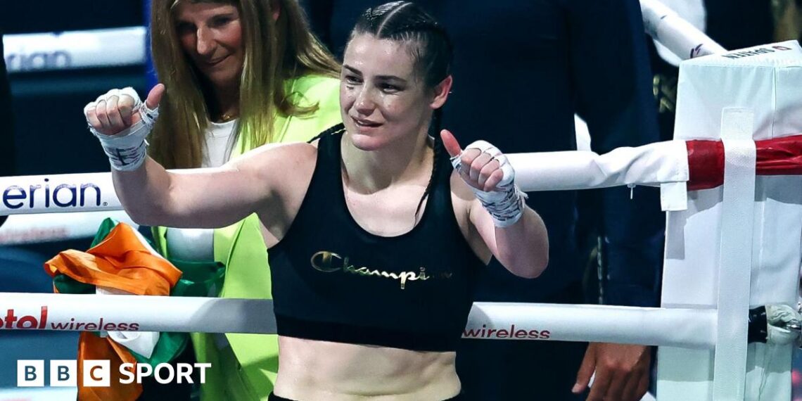 Katie Taylor holds up her thumbs as she stands in a boxing ring