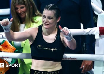 Katie Taylor holds up her thumbs as she stands in a boxing ring